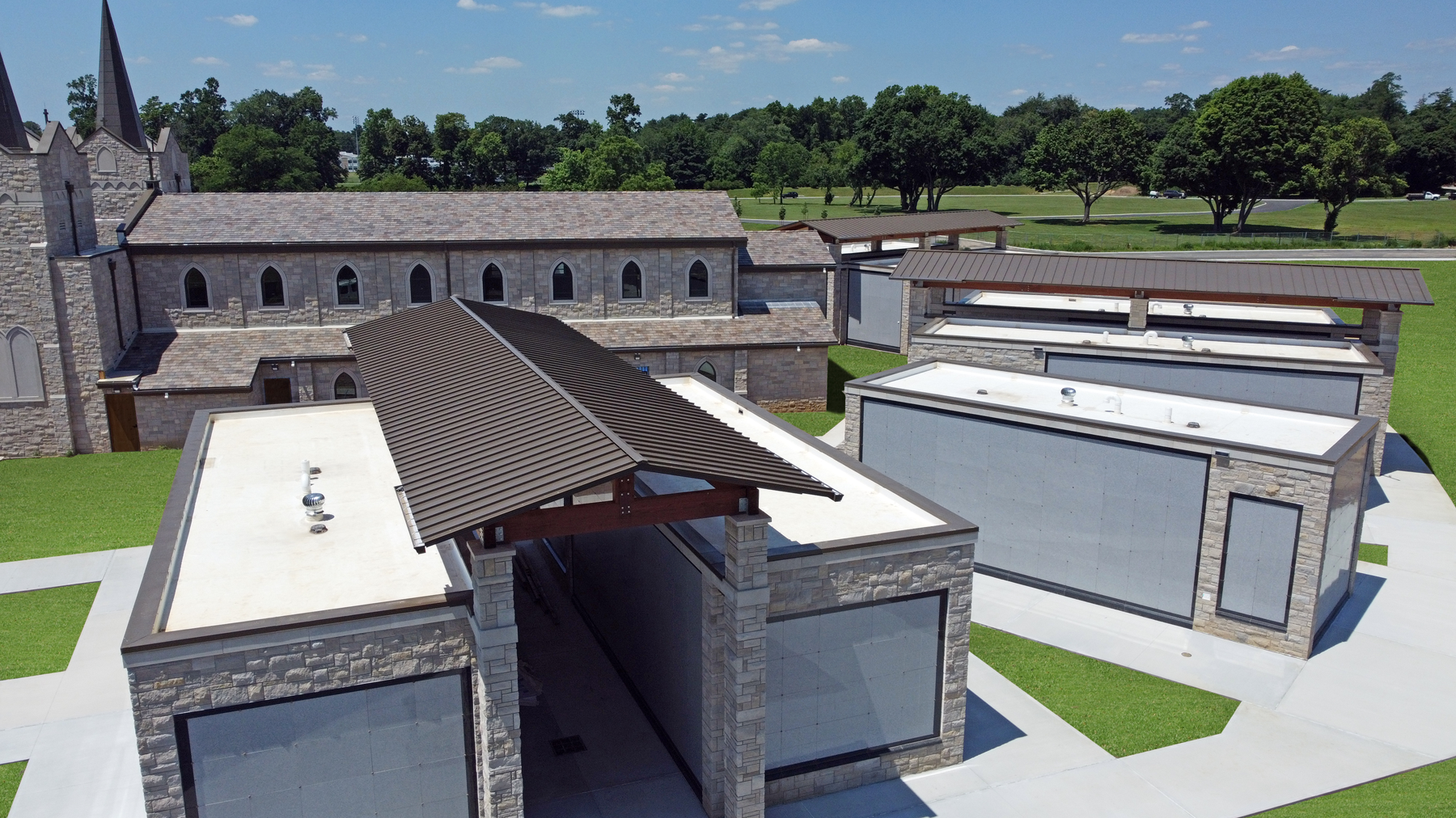 alt="Newly renovated roof on stone building featuring brown colored metal roofing panels"