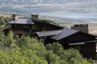 alt="Lake house renovated with new dark bronze roofing panels"