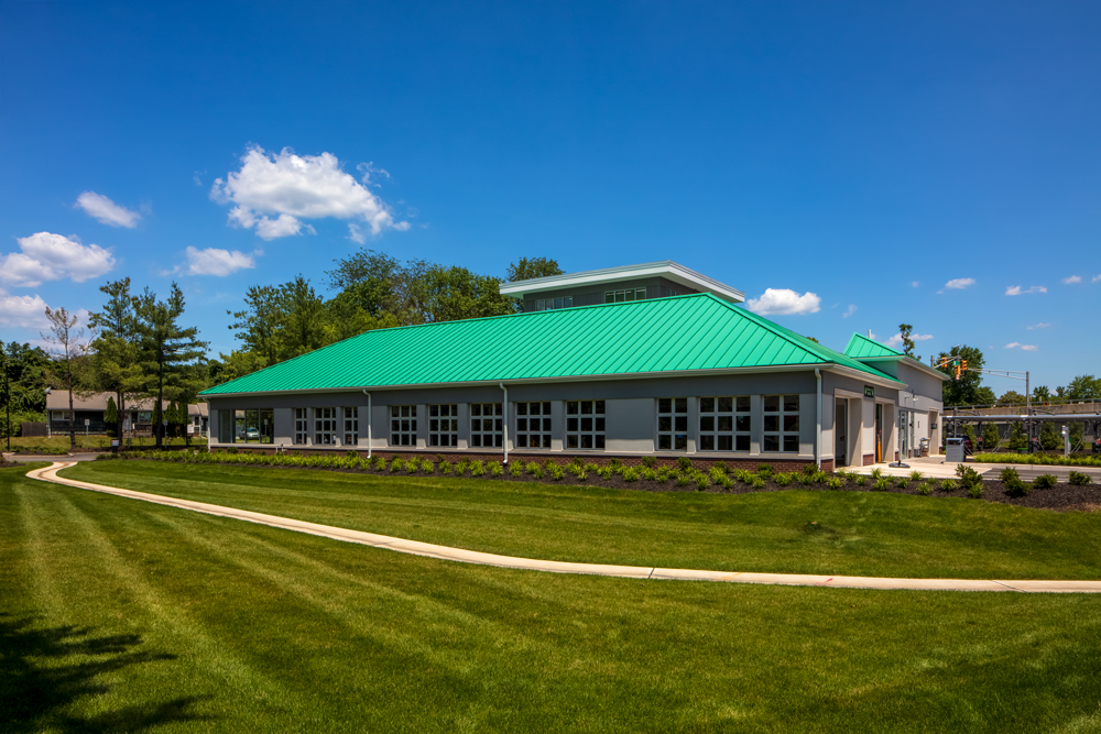 The exterior of a white company building with a turquoise metal roof