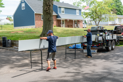 An image of two workmen using a rollforming machine in a neighborhood on the street.