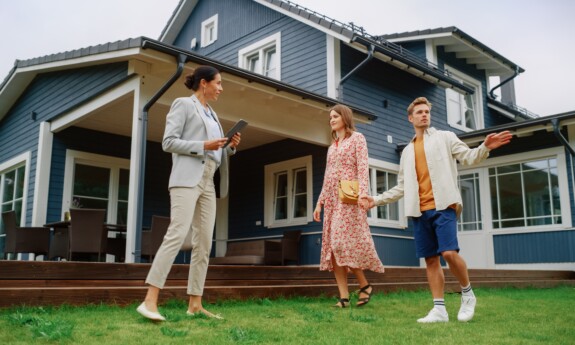 A couple with a realtor outside a home discussing the roof.
