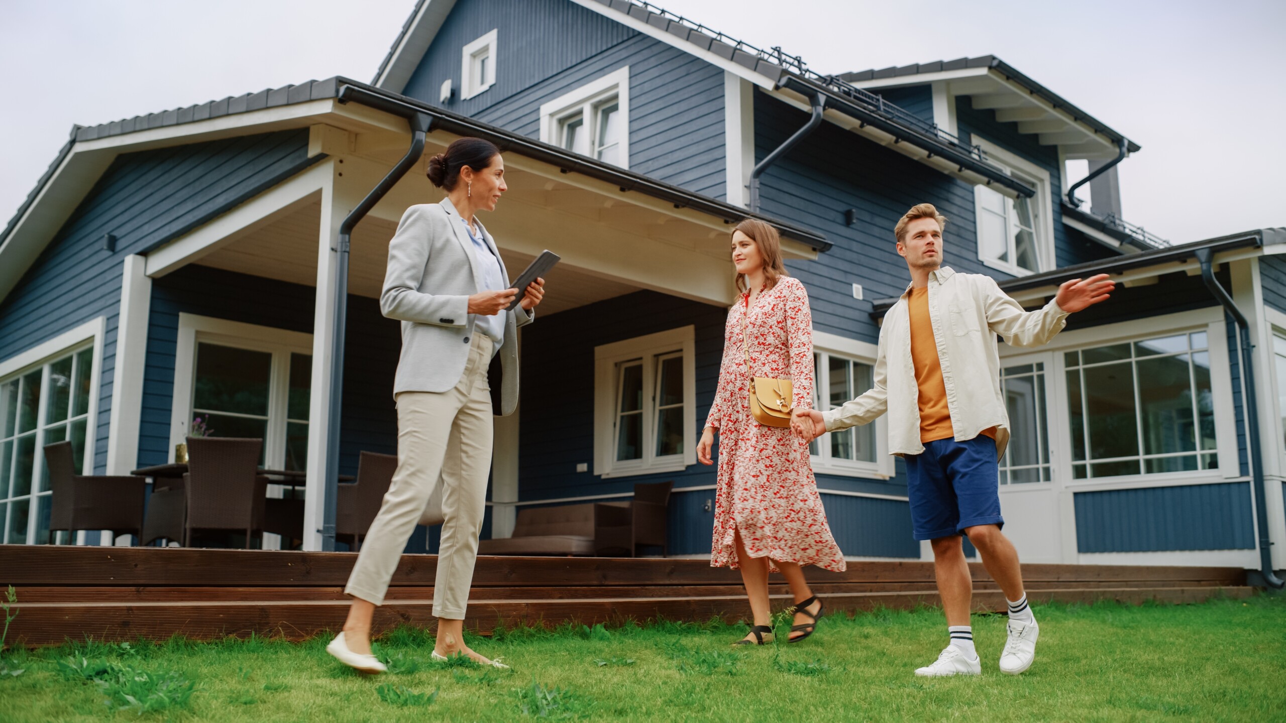 A couple with a realtor outside a home discussing the roof.