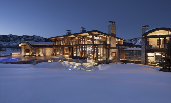 A large house at sunset surrounded by snow.
