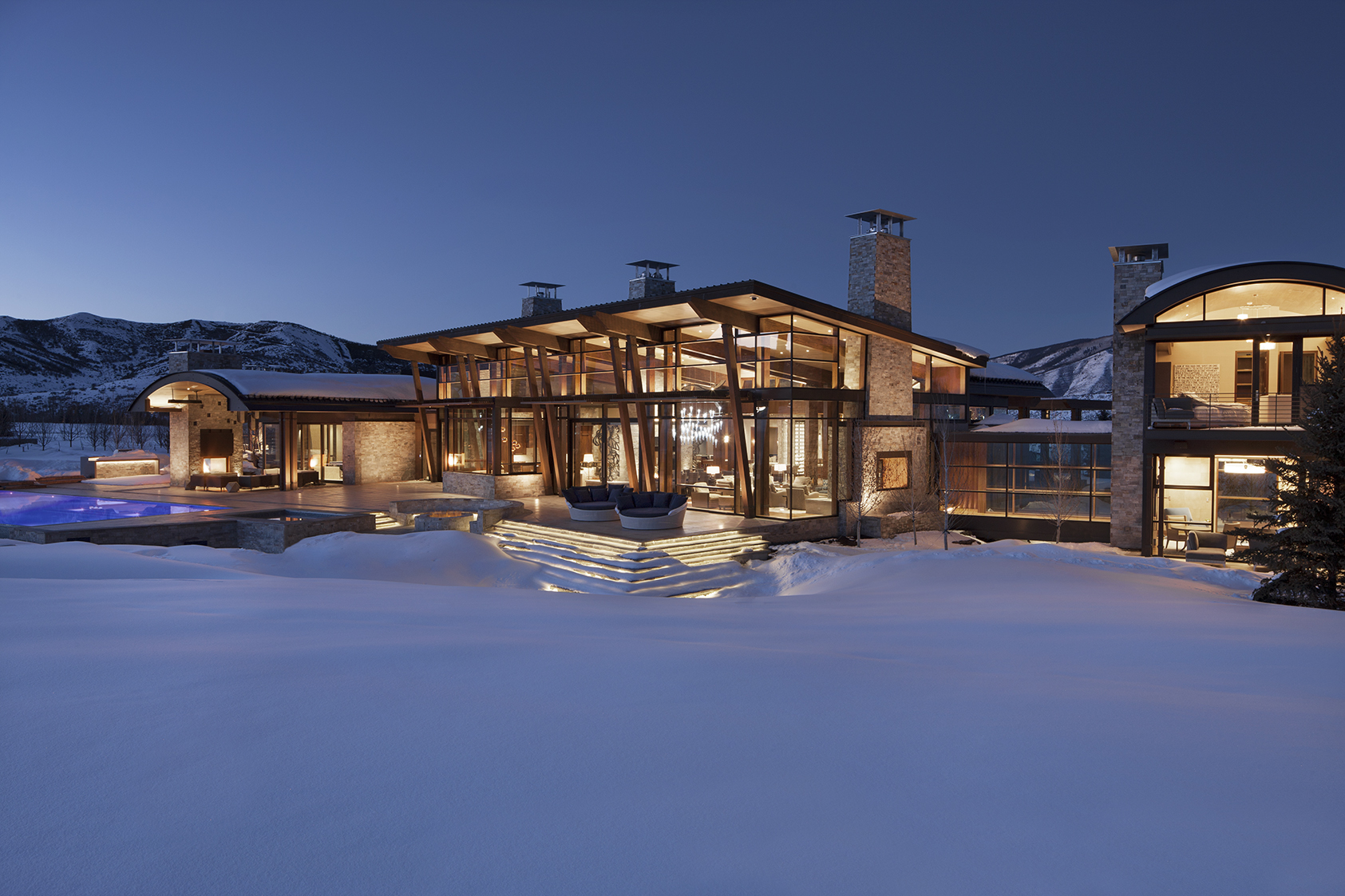 A large house at sunset surrounded by snow.